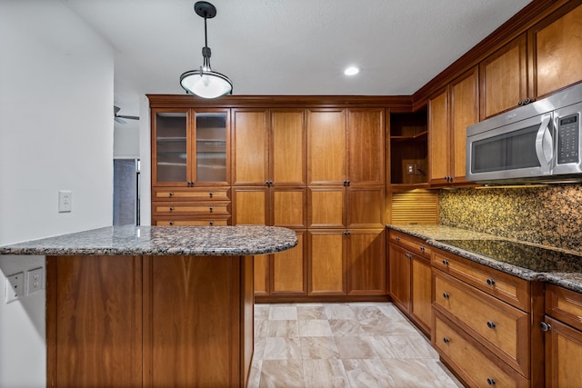 kitchen with pendant lighting, backsplash, dark stone counters, black electric stovetop, and kitchen peninsula