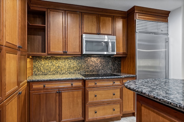 kitchen with appliances with stainless steel finishes, tasteful backsplash, and dark stone countertops