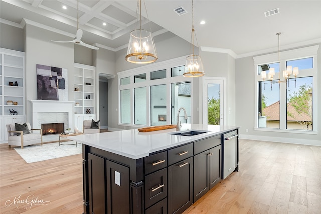 kitchen featuring ornamental molding, a kitchen island with sink, sink, a premium fireplace, and light hardwood / wood-style floors