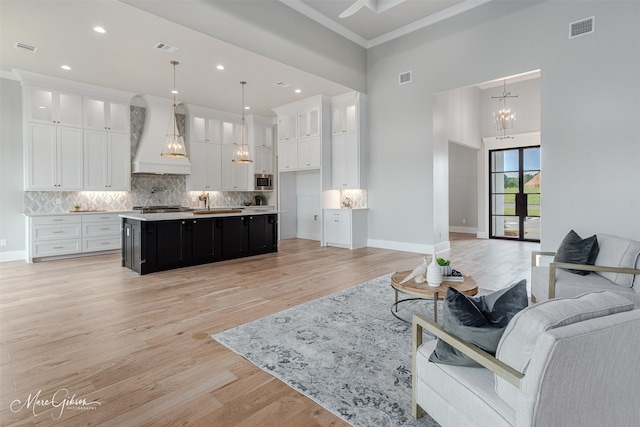 living room featuring visible vents, baseboards, a notable chandelier, and light wood-style flooring