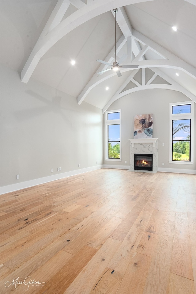 unfurnished living room with a fireplace, lofted ceiling with beams, and light hardwood / wood-style flooring