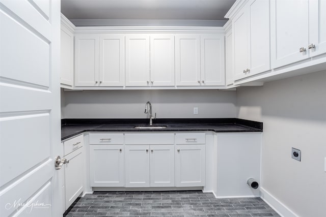 washroom featuring cabinet space, baseboards, hookup for an electric dryer, and a sink