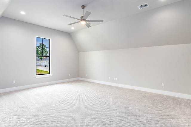 additional living space with visible vents, light carpet, baseboards, and vaulted ceiling