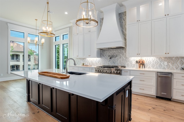 kitchen with custom exhaust hood, light countertops, stainless steel gas stove, and a sink