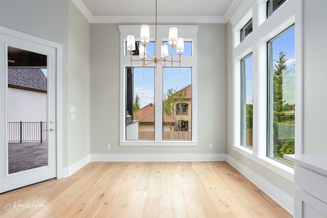 unfurnished dining area featuring ornamental molding, a chandelier, and light hardwood / wood-style floors