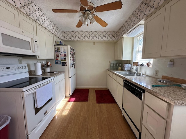 kitchen with a textured ceiling, light hardwood / wood-style floors, white appliances, and sink