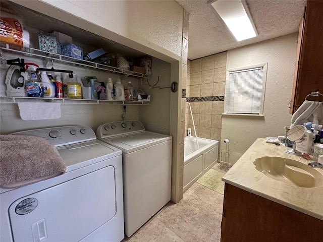 laundry room featuring a textured ceiling, sink, and washing machine and clothes dryer