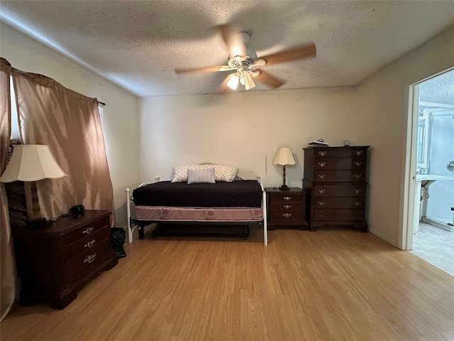 bedroom featuring a textured ceiling, ensuite bathroom, light hardwood / wood-style flooring, and ceiling fan