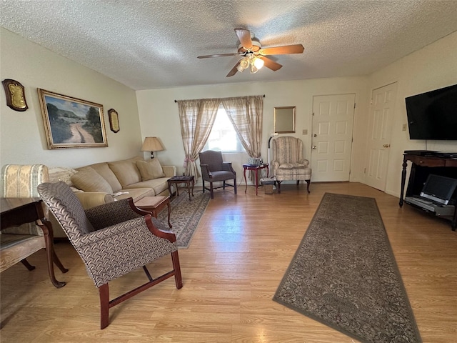 living room featuring ceiling fan, a textured ceiling, and light hardwood / wood-style flooring