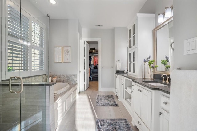 bathroom with plus walk in shower, vanity, a healthy amount of sunlight, and tile patterned flooring