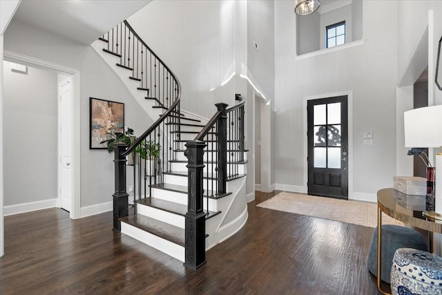 foyer entrance featuring a towering ceiling and dark wood-type flooring