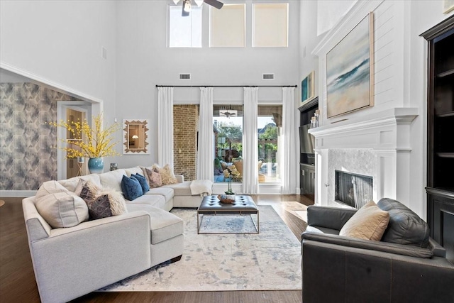 living room featuring hardwood / wood-style floors, ceiling fan, and a towering ceiling