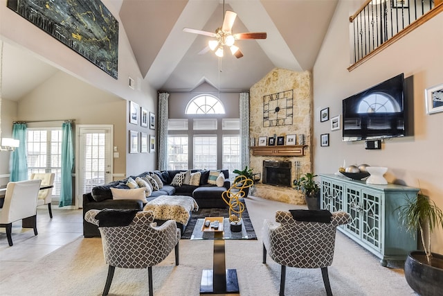 tiled living room featuring ceiling fan, a stone fireplace, and high vaulted ceiling