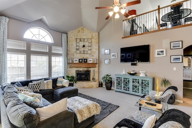 carpeted living room featuring ceiling fan, a stone fireplace, and high vaulted ceiling