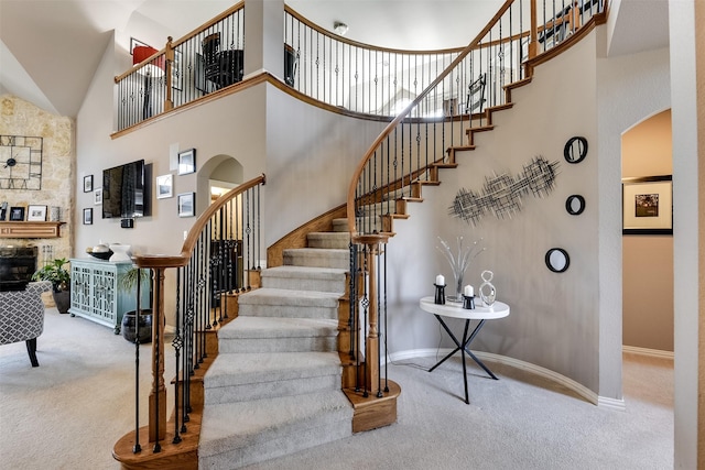 stairway featuring a towering ceiling and carpet floors