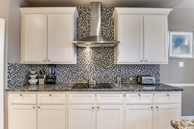 kitchen featuring white cabinetry, wall chimney range hood, and tasteful backsplash