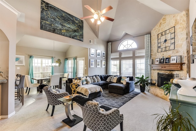 carpeted living room with ceiling fan, a stone fireplace, and a towering ceiling