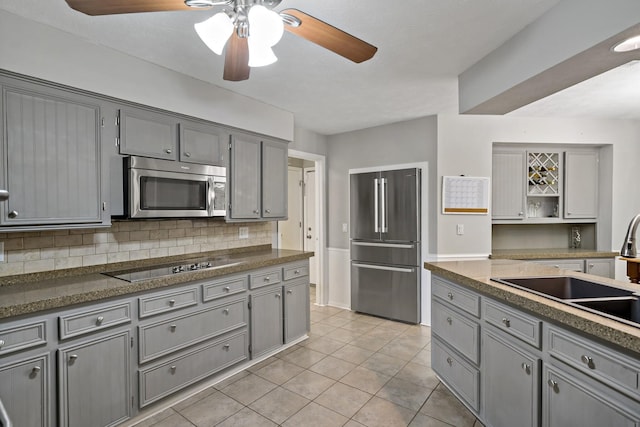 kitchen with decorative backsplash, stainless steel appliances, sink, light tile patterned floors, and gray cabinets