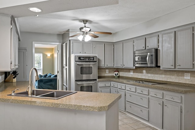 kitchen featuring sink, stainless steel appliances, kitchen peninsula, gray cabinets, and decorative backsplash