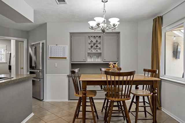 tiled dining space with a chandelier and a textured ceiling