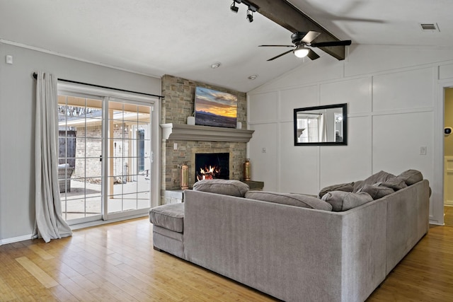 living room with vaulted ceiling with beams, ceiling fan, a fireplace, and light wood-type flooring