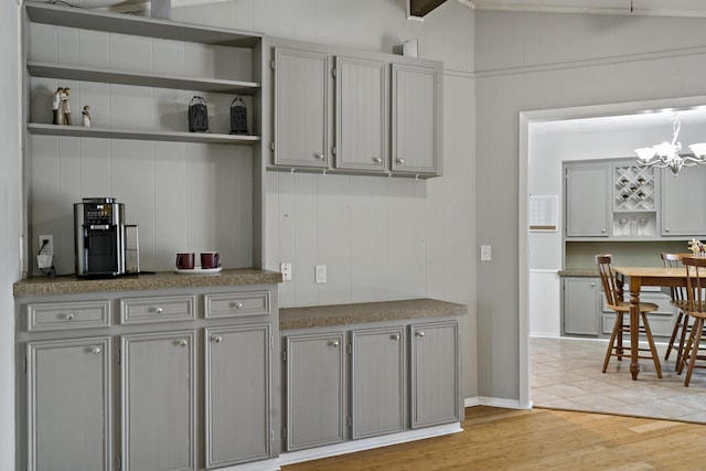 kitchen featuring gray cabinets, a chandelier, decorative light fixtures, and light wood-type flooring