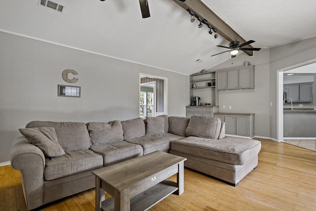 living room with vaulted ceiling with beams, ceiling fan, light wood-type flooring, and rail lighting