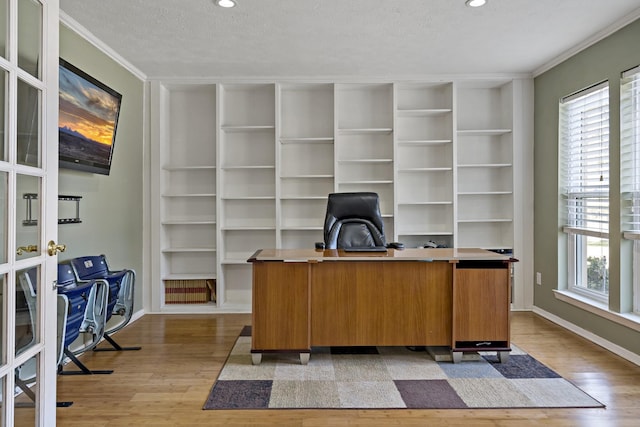 office featuring a textured ceiling, plenty of natural light, built in features, and light wood-type flooring