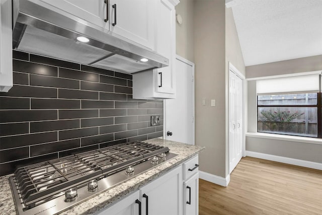 kitchen with white cabinetry, light stone countertops, tasteful backsplash, range hood, and stainless steel gas stovetop