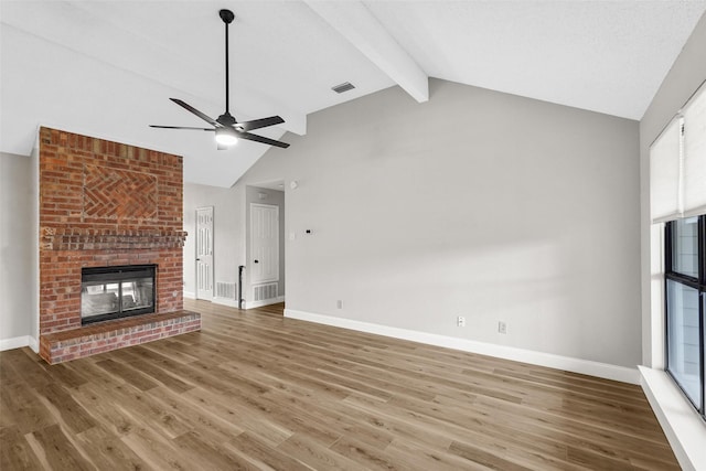 unfurnished living room with ceiling fan, a fireplace, lofted ceiling with beams, and wood-type flooring