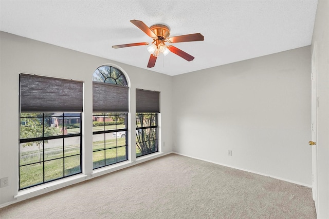 carpeted empty room featuring ceiling fan and a textured ceiling