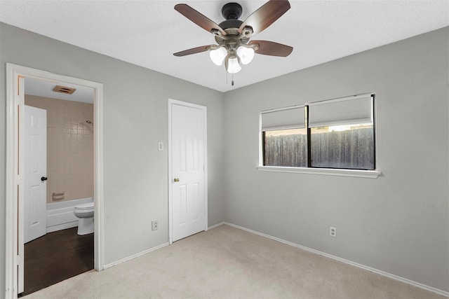 unfurnished bedroom with connected bathroom, ceiling fan, a closet, and light carpet