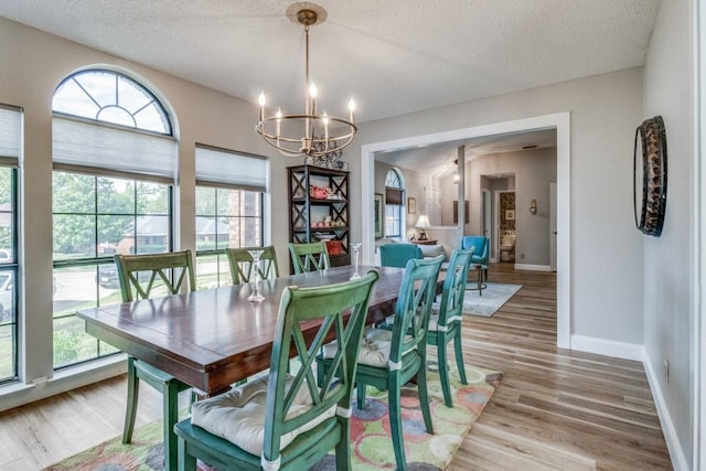 dining area with wood-type flooring, a textured ceiling, and a notable chandelier