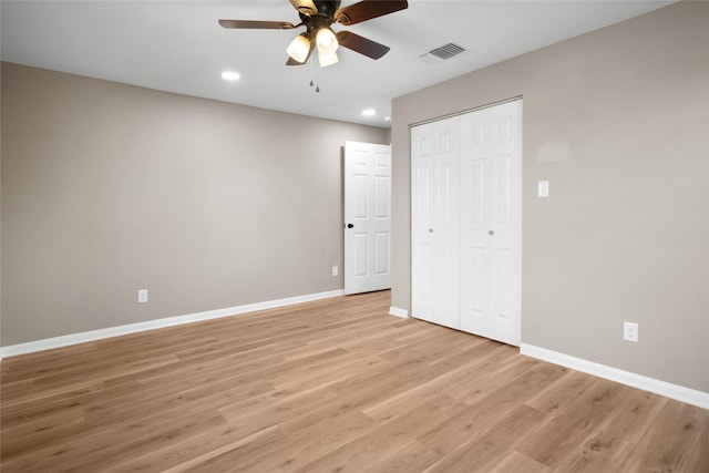 unfurnished bedroom with ceiling fan, light wood-type flooring, and a closet