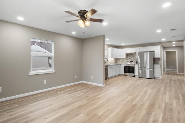 kitchen featuring ceiling fan, decorative backsplash, appliances with stainless steel finishes, light hardwood / wood-style floors, and white cabinetry