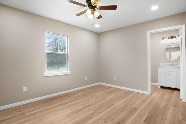 unfurnished bedroom with ensuite bathroom, ceiling fan, and light wood-type flooring