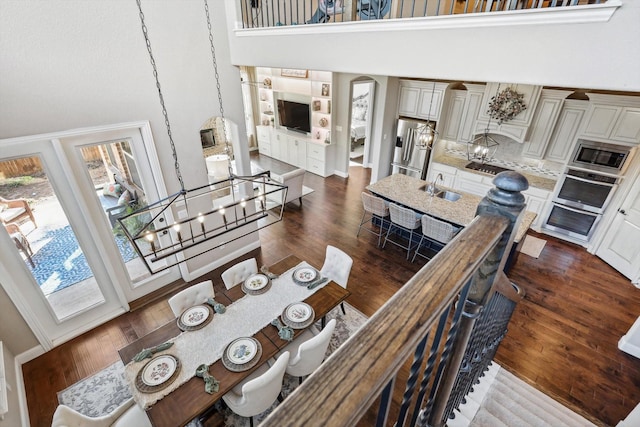 living room featuring sink, a high ceiling, dark hardwood / wood-style flooring, built in features, and a notable chandelier