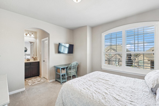 bedroom featuring ensuite bathroom and light colored carpet