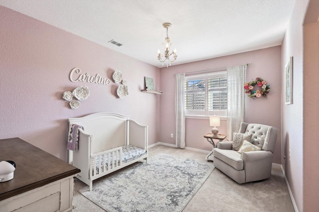 carpeted bedroom with a chandelier, a textured ceiling, and a nursery area