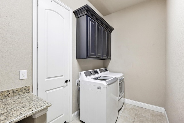 laundry area with washer and clothes dryer, light tile patterned floors, and cabinets