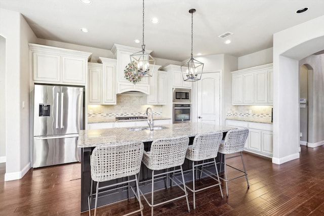 kitchen featuring white cabinets, stainless steel appliances, a center island with sink, and sink