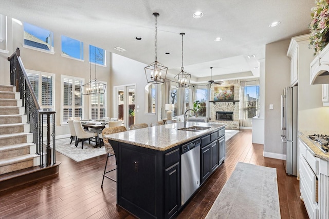 kitchen with light stone countertops, a kitchen breakfast bar, stainless steel appliances, sink, and an island with sink