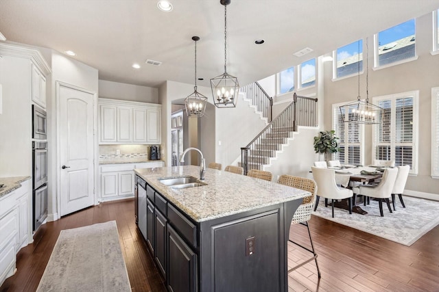 kitchen featuring a kitchen bar, a center island with sink, white cabinets, and appliances with stainless steel finishes