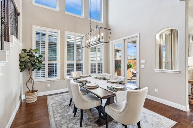 dining room featuring a chandelier, a towering ceiling, and dark wood-type flooring