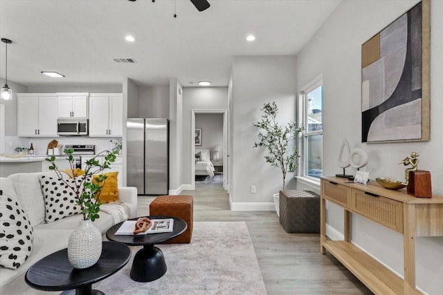 living room featuring ceiling fan and light hardwood / wood-style floors