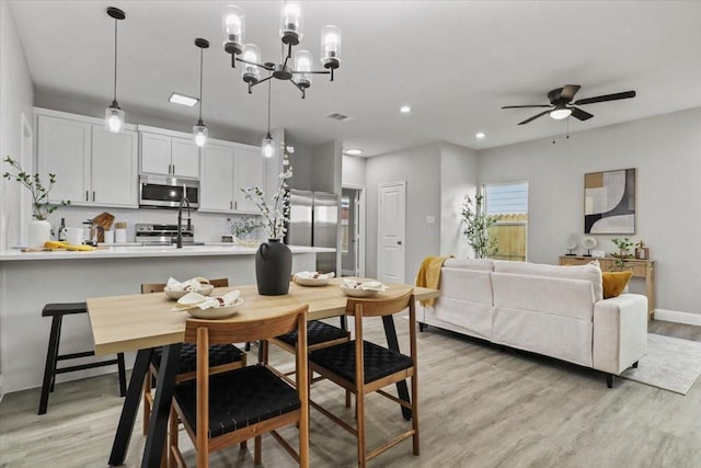 dining space with light hardwood / wood-style flooring and ceiling fan with notable chandelier