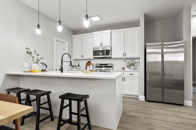 kitchen with pendant lighting, white cabinetry, sink, and appliances with stainless steel finishes