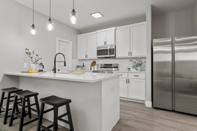 kitchen featuring hanging light fixtures, a breakfast bar area, decorative backsplash, white cabinetry, and stainless steel appliances