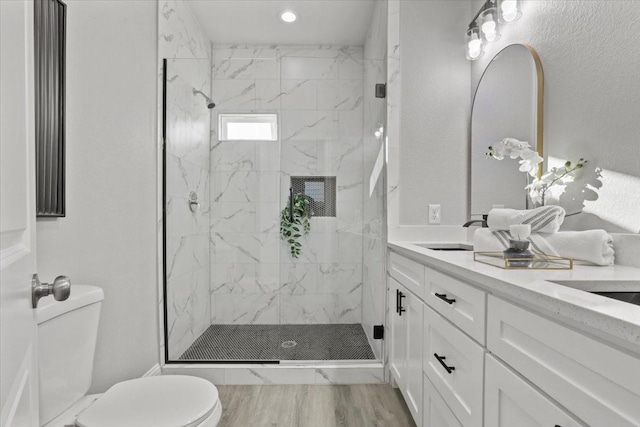 bathroom with tiled shower, hardwood / wood-style flooring, vanity, and toilet