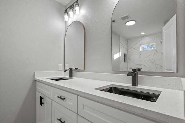 bathroom with a tile shower and vanity